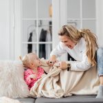 A joyful mother and daughter playing on a couch, embodying warmth and togetherness indoors.