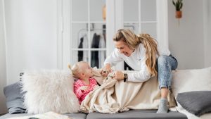 A joyful mother and daughter playing on a couch, embodying warmth and togetherness indoors.